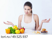 Doubting the girl with a healthy diet and sweet on a white background. Стоковое фото, агентство Ingram Publishing / Фотобанк Лори