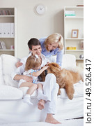 Smiling family pat the dog at home. Стоковое фото, агентство Ingram Publishing / Фотобанк Лори