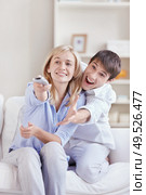 The man reaches for the panel from the TV that keeps a girl. Стоковое фото, агентство Ingram Publishing / Фотобанк Лори