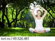 A young woman meditating in park. Стоковое фото, агентство Ingram Publishing / Фотобанк Лори