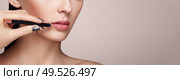Beautiful woman paints lips with lipstick. Beautiful woman face. Makeup detail. Beauty girl with perfect skin. Lips and nails manicure. Стоковое фото, агентство Ingram Publishing / Фотобанк Лори