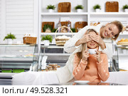 The young girl closes eyes to the girlfriend in cafe. Стоковое фото, агентство Ingram Publishing / Фотобанк Лори