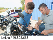 Man making adjustment to motorcycle with spanner. Стоковое фото, агентство Ingram Publishing / Фотобанк Лори