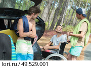 Teenage men by vehicle in woods, one in wheelchair. Стоковое фото, агентство Ingram Publishing / Фотобанк Лори