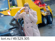 Worried woman on telephone, breakdown lorry in background. Стоковое фото, агентство Ingram Publishing / Фотобанк Лори