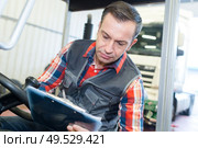 mechanic writing on a clipboard. Стоковое фото, агентство Ingram Publishing / Фотобанк Лори