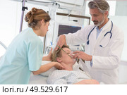 doctor giving oxygen mask to female patient at hospital. Стоковое фото, агентство Ingram Publishing / Фотобанк Лори