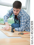 installing laminate flooring fitting the next piece. Стоковое фото, агентство Ingram Publishing / Фотобанк Лори
