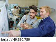 apprentice looking at exploded diagram to see where part fits. Стоковое фото, агентство Ingram Publishing / Фотобанк Лори