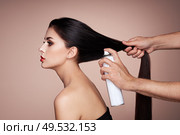 Hairdresser styling woman’s hair. Portrait of beautiful young woman getting haircut. Care for long smooth hair. Стоковое фото, агентство Ingram Publishing / Фотобанк Лори