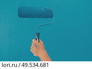 Someone painting white wall in blue color hand holding paint roller. Someone painting wall. Стоковое фото, агентство Ingram Publishing / Фотобанк Лори
