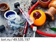 Smoking hookah pipe with mouthpiece and citrus flavored shisha tobacco.. Oriental hookah with orange flavor. Стоковое фото, агентство Ingram Publishing / Фотобанк Лори