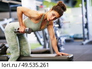Caucasian strong woman lifting some weights and working on her triceps and biceps in a gym with dumbbells.. Woman working on her triceps and biceps in a gym with dumbbells. Стоковое фото, агентство Ingram Publishing / Фотобанк Лори