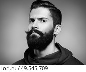 Portrait of handsome man with beard and mustache. Close-up image of serious brutal bearded man on dark background. Black and white photography. Стоковое фото, агентство Ingram Publishing / Фотобанк Лори