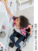 Woman in wheelchair struggling to reach something from shelf. Стоковое фото, агентство Ingram Publishing / Фотобанк Лори