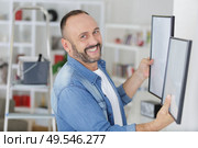 man is deciding where hanging the picture. Стоковое фото, агентство Ingram Publishing / Фотобанк Лори