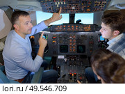 Man showing cockpit controls to young people. Стоковое фото, агентство Ingram Publishing / Фотобанк Лори