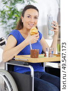 smiling crippled woman sitting in a wheel chair having breakfast. Стоковое фото, агентство Ingram Publishing / Фотобанк Лори