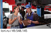 Mechanic guy signs agreement with young woman client. Стоковое видео, видеограф Яков Филимонов / Фотобанк Лори