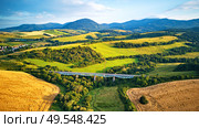 Summer landscape with fields, meadows and railroad bridge in mountains. Aerial view of railway viaduct on the Tatra hills in Slovakia. Стоковое фото, агентство Ingram Publishing / Фотобанк Лори