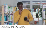 African man sniffs fragrance of perfume, chooses scent spray with pleasant smell. Стоковое видео, видеограф Яков Филимонов / Фотобанк Лори
