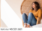 Optimistic woman sitting in a confortable rattan chair at home. Стоковое фото, агентство Ingram Publishing / Фотобанк Лори