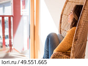 Optimistic woman sitting in a confortable rattan chair at home. Стоковое фото, агентство Ingram Publishing / Фотобанк Лори