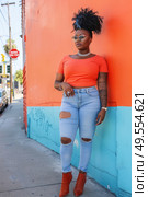 A woman is leaning casually against a wall, dressed in ripped jeans, exuding a relaxed vibe. Стоковое AI-изображение, AI-художник Данила Большаков / Фотобанк Лори