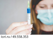 Young woman wearing a face mask and hold a vaccine. Стоковое фото, агентство Ingram Publishing / Фотобанк Лори