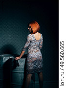 redheaded model girl in a long dress in a dark industrial Studio near barrels of oil. Стоковое фото, агентство Ingram Publishing / Фотобанк Лори