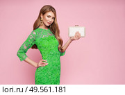 Blonde young woman in elegant green dress. Model posing on a pink background. Jewelry and hairstyle. Girl with handbag. Fashion photo. Spring summer lookbook. Стоковое фото, агентство Ingram Publishing / Фотобанк Лори