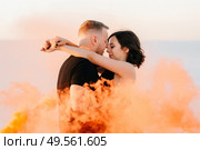 guy and a girl in black clothes hug and run on the white sand with orange smoke. Стоковое фото, агентство Ingram Publishing / Фотобанк Лори