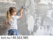 A little girl paints a wall in a new house. Interior decoration of the house, wall painting. Cosmetic repairs. Child labor. Стоковое AI-изображение, AI-художник Photojuli / Фотобанк Лори