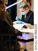 Close-up of Beautician painting her client’s nails in blue and yellow nail varnish in a beauty centre. Close-up of Beautician painting her client’s nails in blue and yellow nail varnish. Стоковое фото, агентство Ingram Publishing / Фотобанк Лори