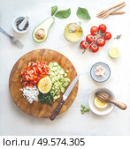 Chopped ingredients for avocado salsa, guacamole  or salad on cutting board. Fresh cut avocado, tomatoes , lemon, lime , olives oil, garlic and chili a on white kitchen table. Top view. Стоковое фото, агентство Ingram Publishing / Фотобанк Лори