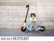 9-year-old girl sitting on an electric scooter in the street. Little girl sitting on an electric scooter in the street. Стоковое фото, агентство Ingram Publishing / Фотобанк Лори