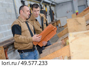 workmen in discussion holding roof tile. Стоковое фото, агентство Ingram Publishing / Фотобанк Лори