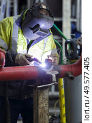 man wearing a mask welding pipes in industry. Стоковое фото, агентство Ingram Publishing / Фотобанк Лори