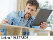 checking on tablet how to assemble a furniture. Стоковое фото, агентство Ingram Publishing / Фотобанк Лори