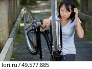 woman attempting to repair her bicycle wheel. Стоковое фото, агентство Ingram Publishing / Фотобанк Лори