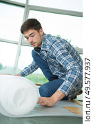Man unrolling insulation on floor. Стоковое фото, агентство Ingram Publishing / Фотобанк Лори