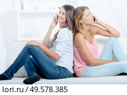 two girls with smartphones sitting on sofa at home. Стоковое фото, агентство Ingram Publishing / Фотобанк Лори