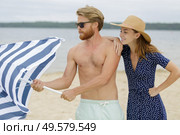 couple putting down the parasol on the beach. Стоковое фото, агентство Ingram Publishing / Фотобанк Лори