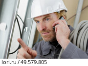builder on the phone with equipment indoors. Стоковое фото, агентство Ingram Publishing / Фотобанк Лори
