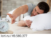 young tired brown-haired man waking stop alarm. Стоковое фото, агентство Ingram Publishing / Фотобанк Лори