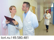 Doctor looking at clipboard in hospital corridor. Стоковое фото, агентство Ingram Publishing / Фотобанк Лори