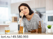 miserable young drunk woman sat at table at home. Стоковое фото, агентство Ingram Publishing / Фотобанк Лори