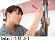 handywoman holding a level ruler on a table. Стоковое фото, агентство Ingram Publishing / Фотобанк Лори
