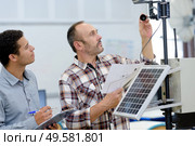 electricians measuring solar panels prior to instalation. Стоковое фото, агентство Ingram Publishing / Фотобанк Лори