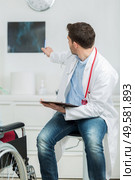 male doctor pointing and showing a scan to disabled patient. Стоковое фото, агентство Ingram Publishing / Фотобанк Лори